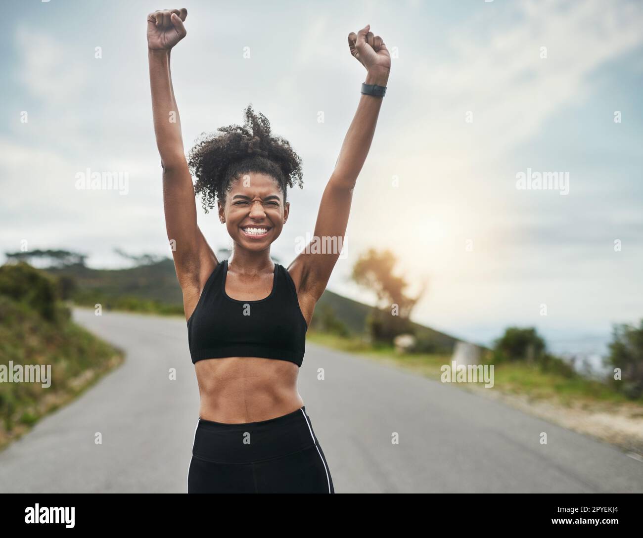 Sie will die Welt erobern. Eine attraktive junge Sportlerin jubelt draußen bei der Feier. Stockfoto