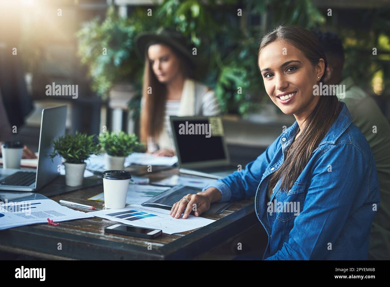 Wir ziehen es vor, unseren Arbeitsbereich hin und wieder zu ändern. Porträt einer jungen Designerin, die sich mit ihren Kollegen in einem Café trifft. Stockfoto