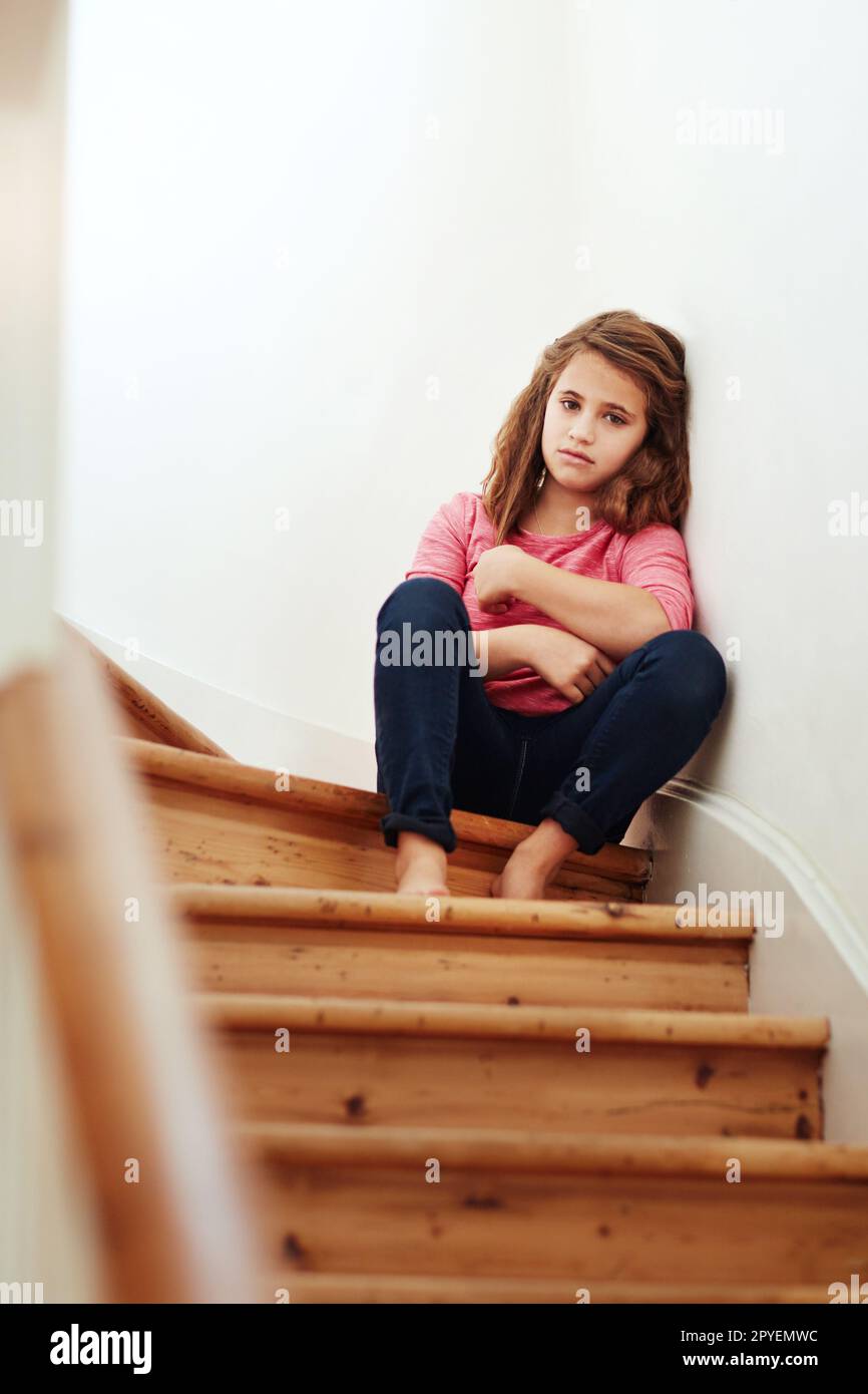 Ich fühle mich hier so allein. Ein kleines Mädchen, das traurig aussah, als es zu Hause auf der Treppe saß. Stockfoto