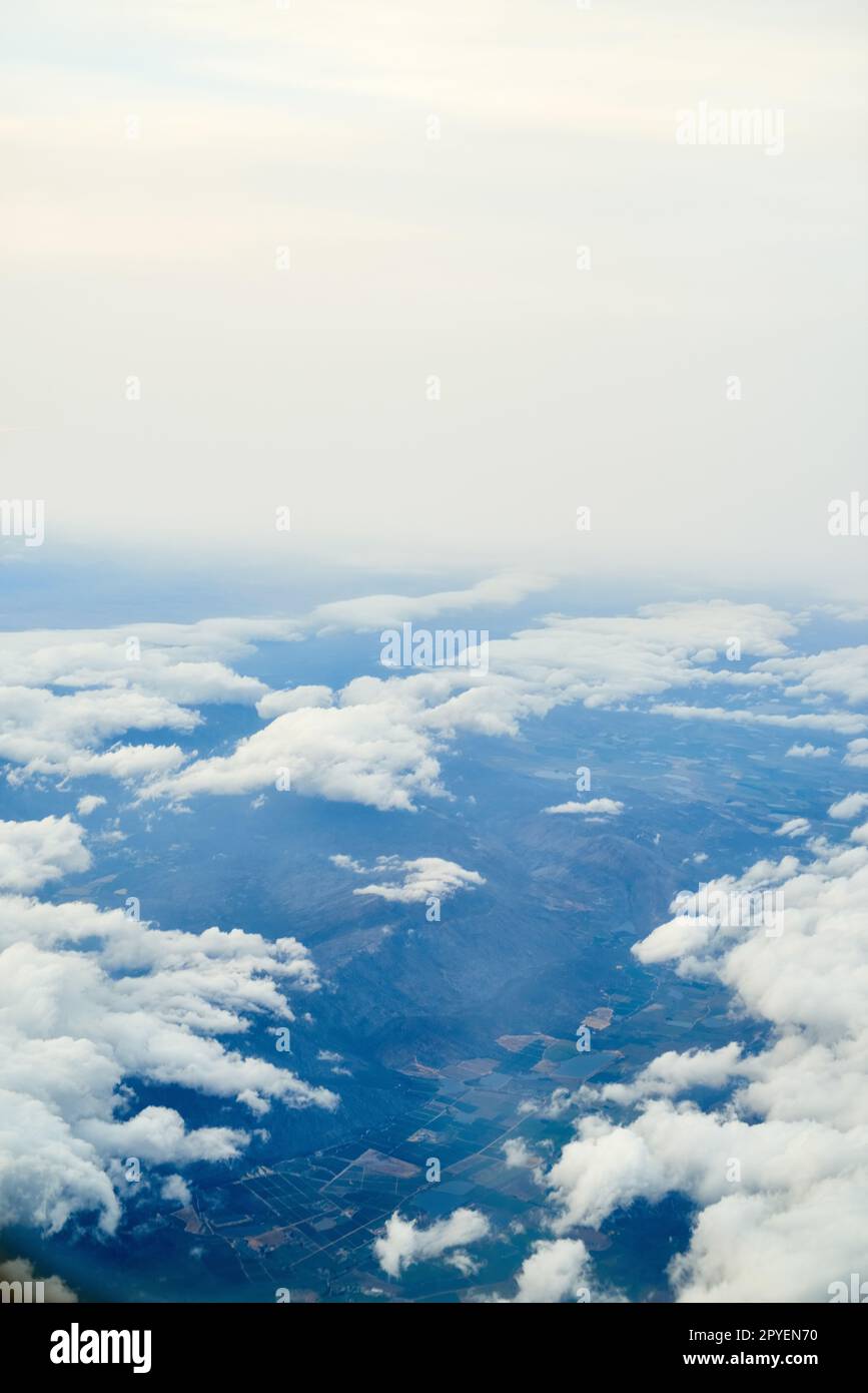 Die Welt ist so schön von oben. Ein wolkiger Blick von einem Flugzeugfenster. Stockfoto