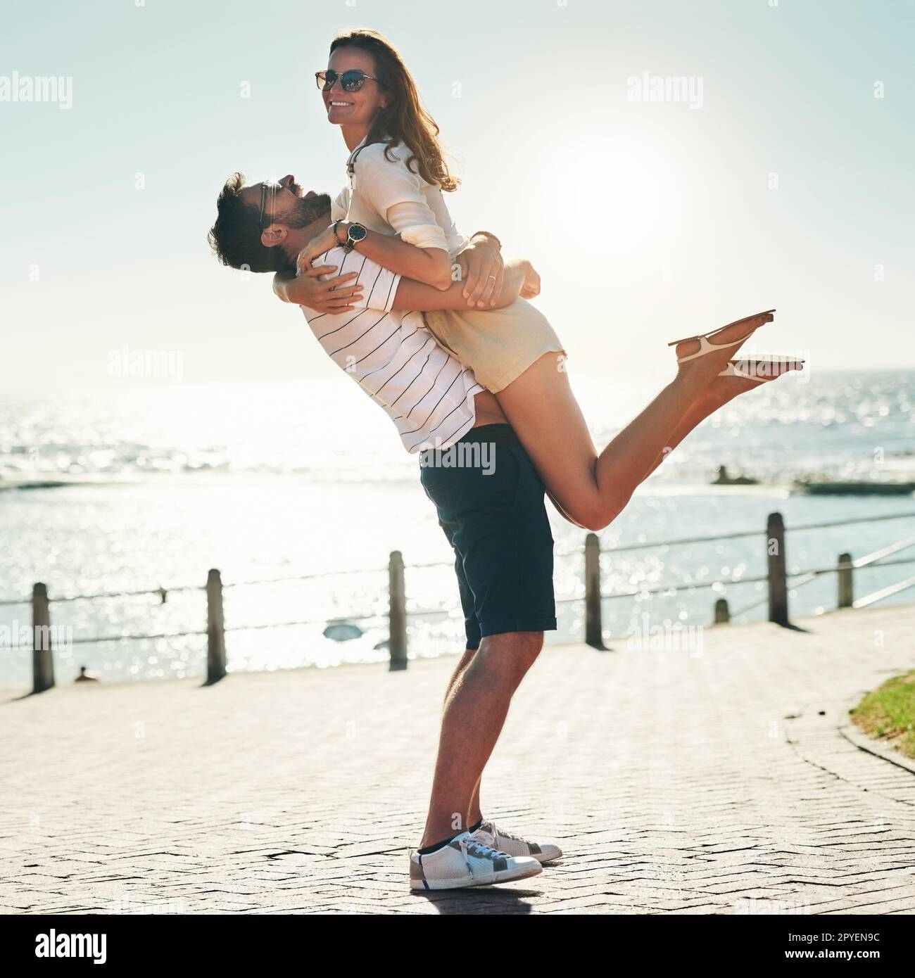 Sommerromantik-Tore. Aufnahme eines glücklichen jungen Paares in voller Länge, das einen Sommertag im Freien umarmt. Stockfoto