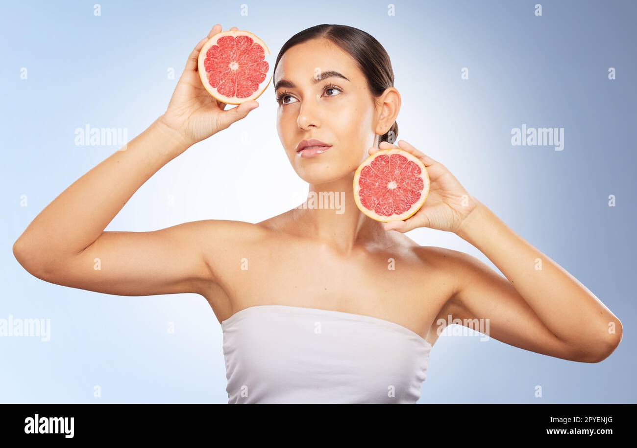 Frau, Schönheit und natürliche Hautpflege mit Grapefruit, strahlendem Glanz und gesunder Ästhetik auf blauem Hintergrund. Modell, Hautglänz und Obst für Wellness, Selbstpflege und kosmetische Gesundheit im Studiohintergrund Stockfoto