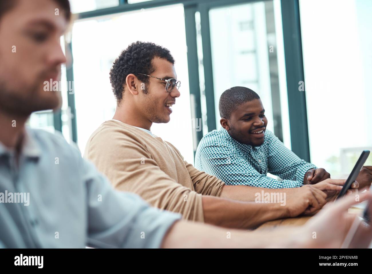 Fusion von Unternehmen und Online-Welt. Zwei junge Designer, die in einem Büro an einem digitalen Tablet arbeiten. Stockfoto