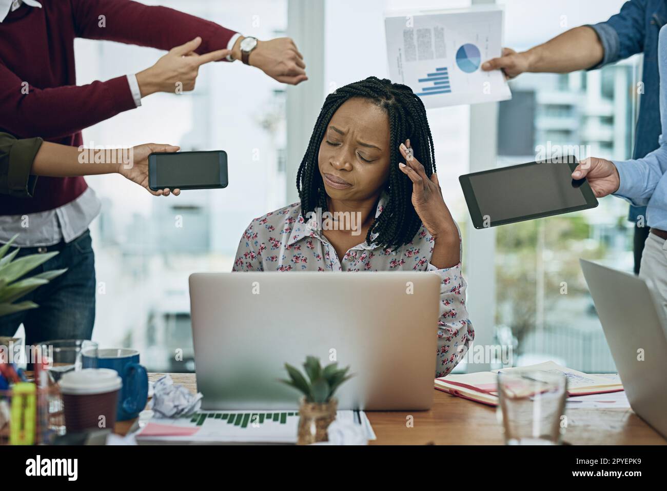 Ertrinken in den Anforderungen des Arbeitstages. Eine junge Geschäftsfrau, die in einer anspruchsvollen Büroumgebung gestresst aussieht. Stockfoto