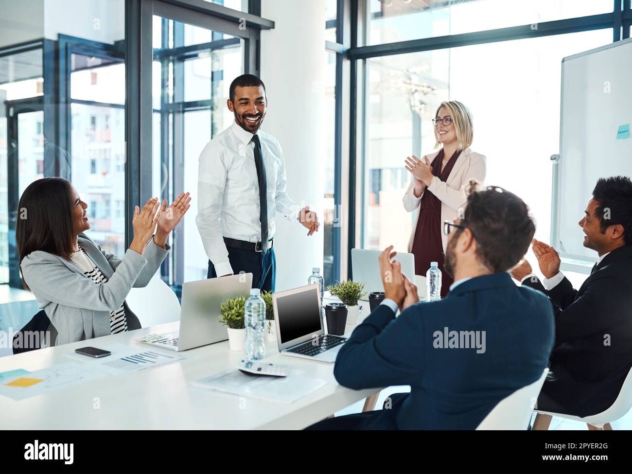Er hat sich dem Team wieder einmal bewiesen. Geschäftsleute applaudieren einem Kollegen in einem Büro. Stockfoto