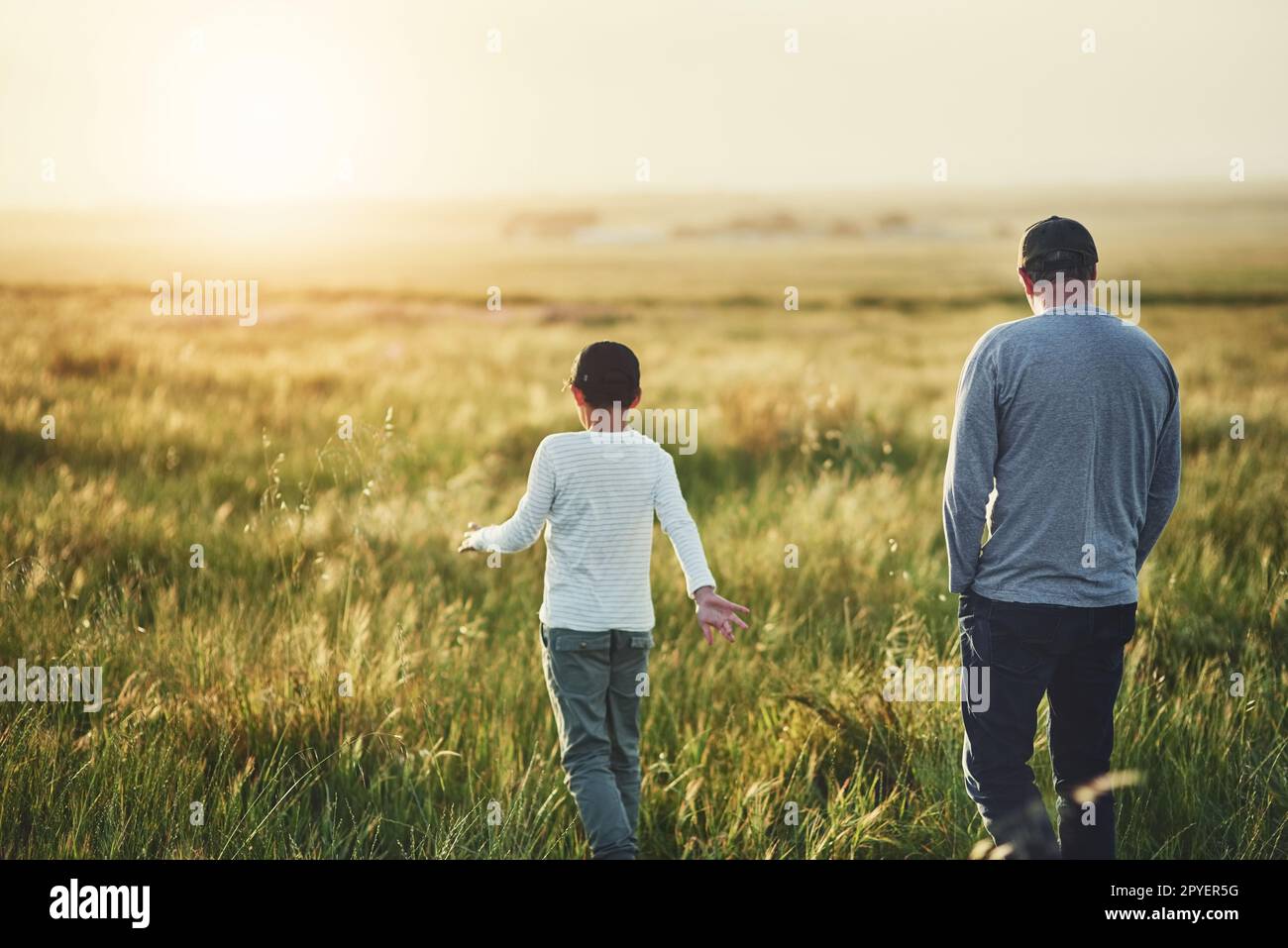 Vater-Sonne-Zeit ist unbezahlbar. Rückansicht eines Vaters und seines Sohnes auf einem Feld. Stockfoto