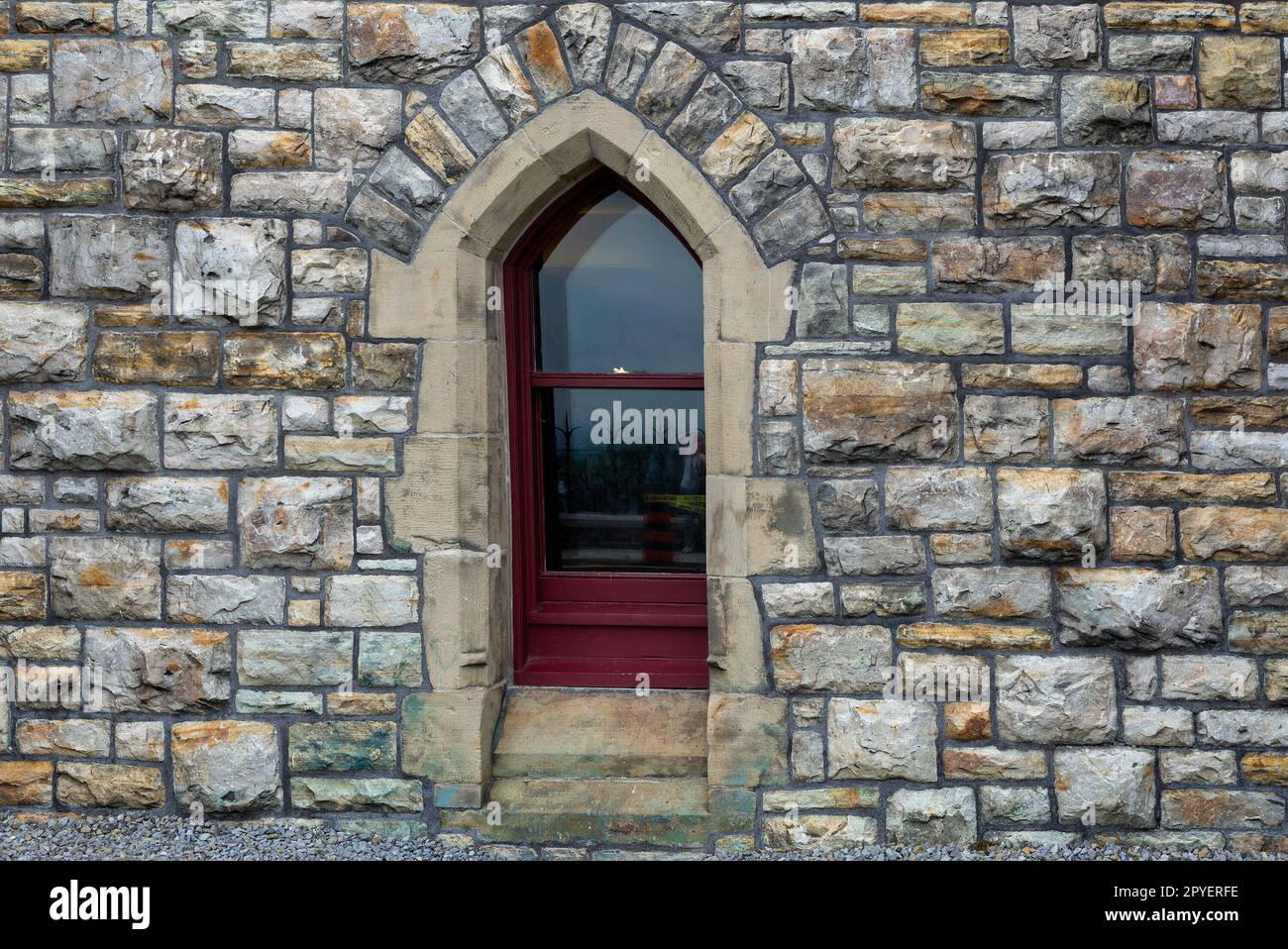 Ein kleines, wunderschönes Fenster im gotischen Stil auf einer Steinmauer Stockfoto