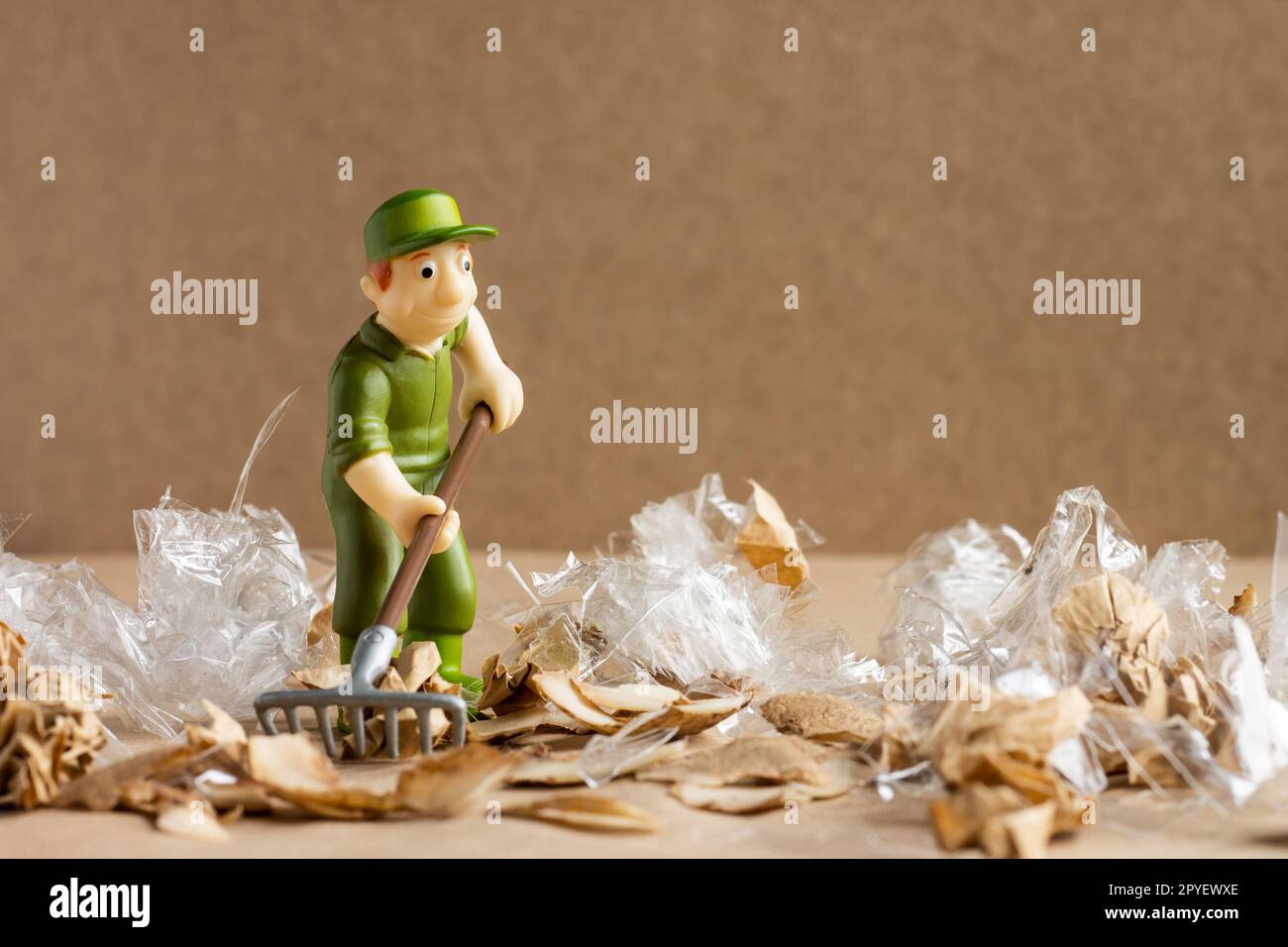 Ein Spielzeugmann im Arbeiteranzug macht eine große Menge Müll. Umweltschutz und Ökologiekonzept. Stockfoto