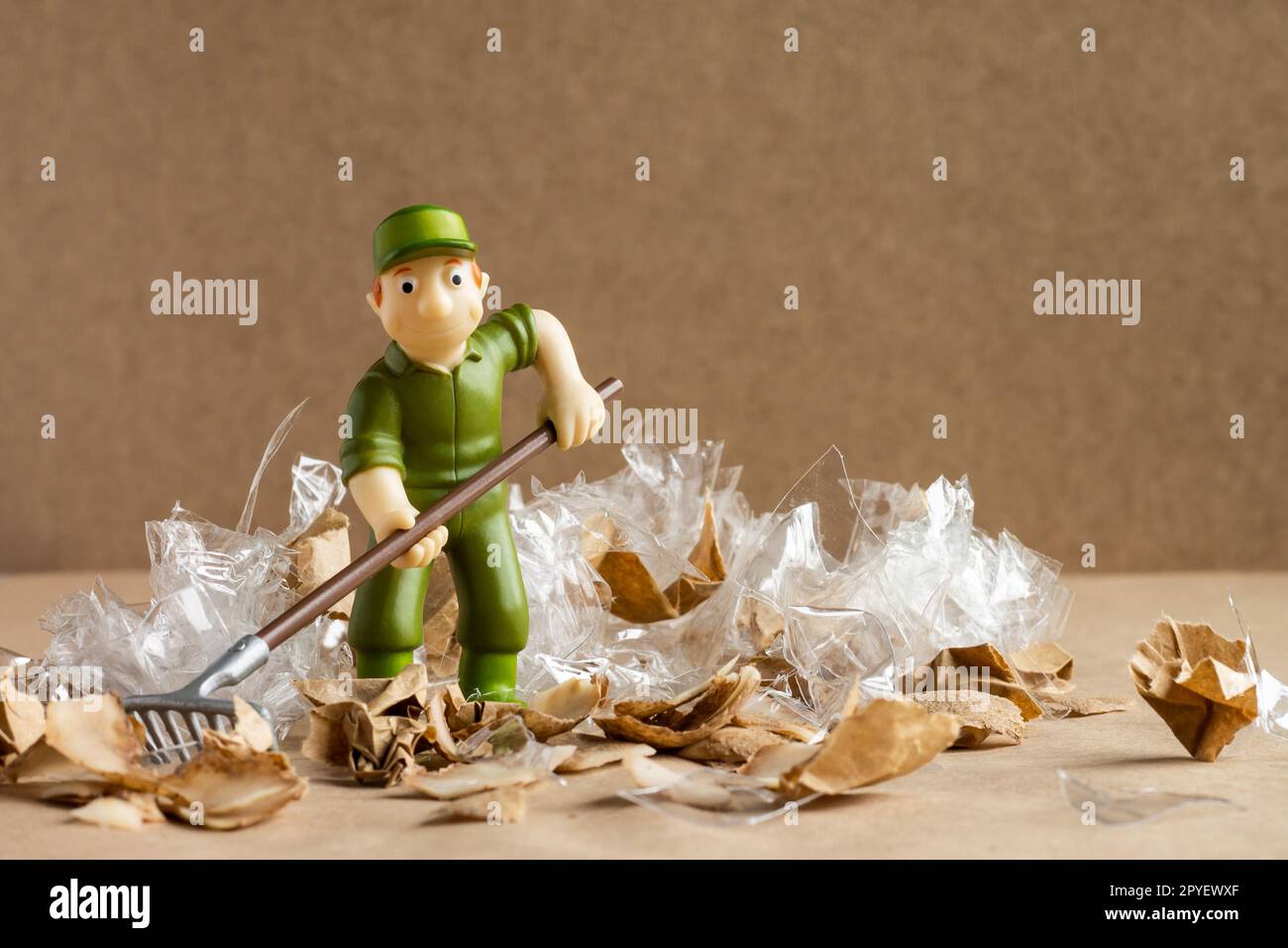 Ein Spielzeugmann im Arbeiteranzug macht eine große Menge Müll. Umweltschutz und Ökologiekonzept. Stockfoto