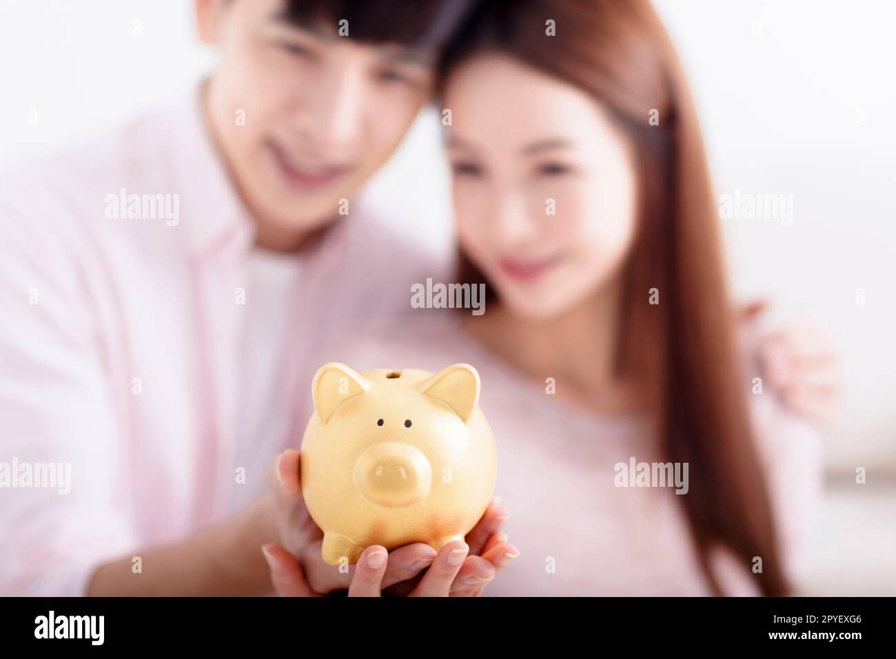 Glückliches Paar, das Piggybank hält und für die Zukunft Einsparungen macht Stockfoto