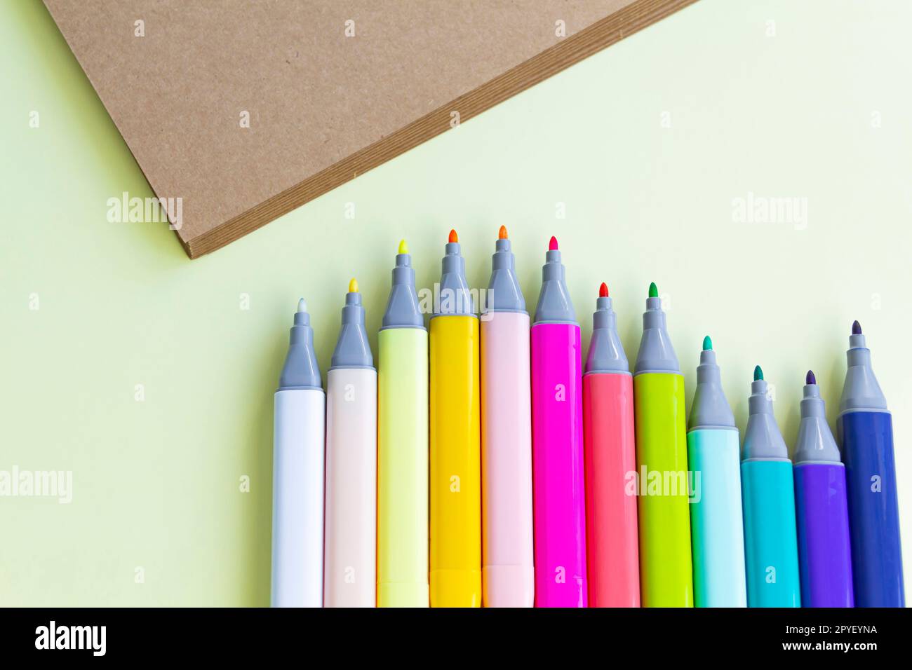 Viele bunte Filzstifte zum Zeichnen in einem Notizbuch und Album auf gelbem Hintergrund. Stockfoto