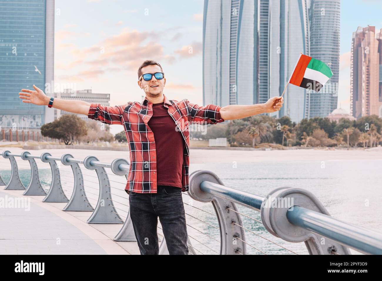 Ein freiberuflicher Arbeiter oder Student begrüßt die Flagge der Vereinigten Arabischen Emirate, die sein Engagement für die Werte und ideale der Nation in der Nähe der Wolkenkratzer von Abu Dhabi symbolisiert Stockfoto