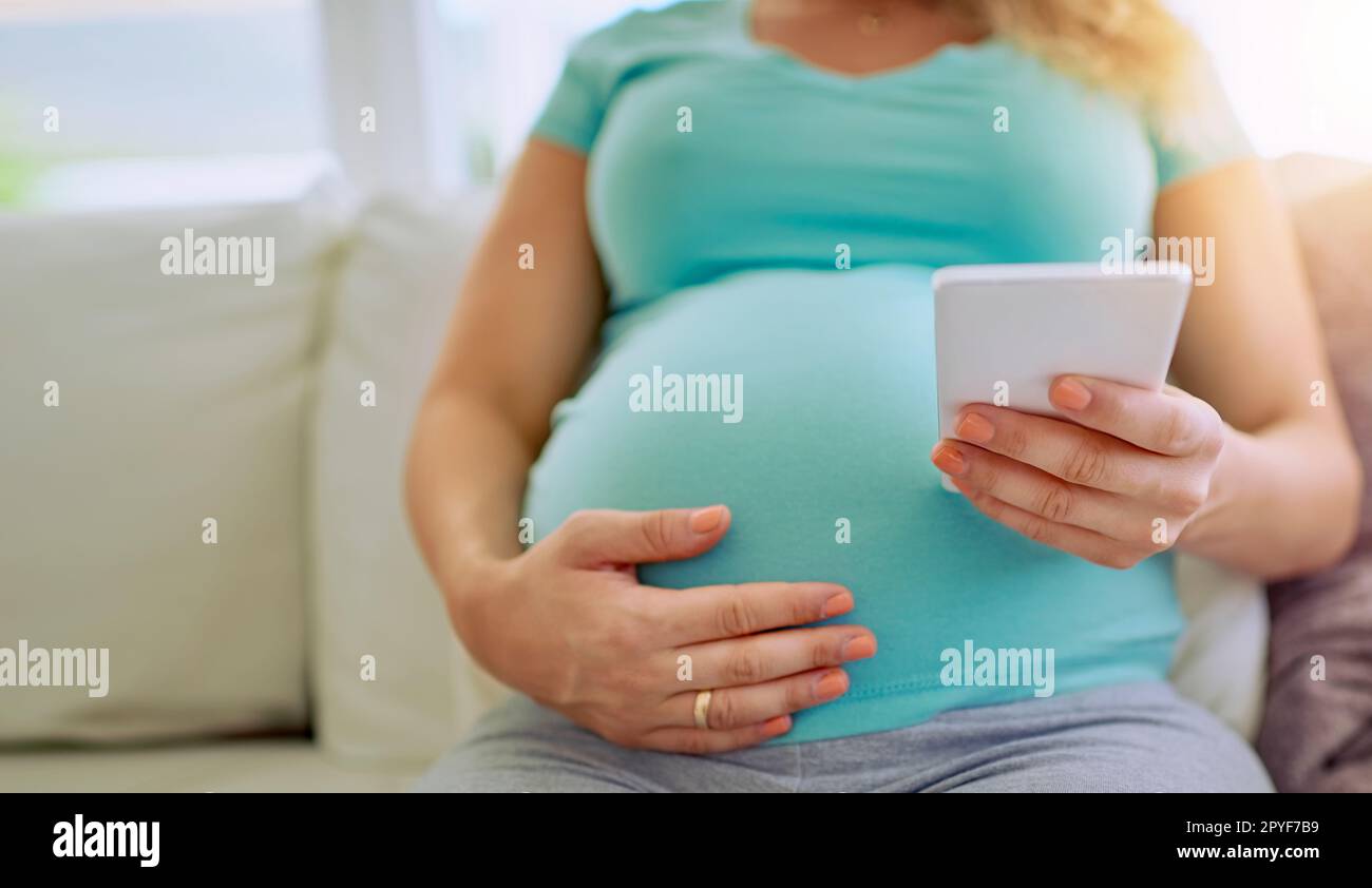 Ich schicke einen Countdown zu ihren engen. Nahaufnahme einer schwangeren Frau, die zu Hause auf ihrem Handy simst. Stockfoto