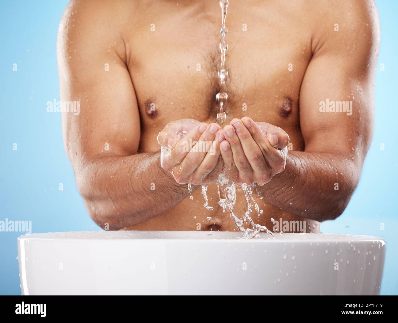 Mann, Wasser oder Händewaschen auf blauem Hintergrund für die Pflege der Körperhygiene, Gesundheit Wellness oder Hautpflege Routine. Modell, Wasserspritzer oder laufende Dusche zur Reinigung von Bakterien oder zur Selbstpflege Stockfoto