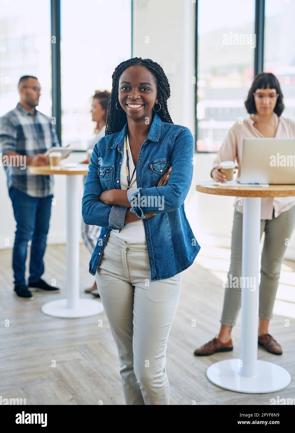 Waren das erfolgreiche Start-up, über das jeder sprach. Porträt einer selbstbewussten jungen Frau, die in einem modernen Büro mit ihren Kollegen im Hintergrund steht. Stockfoto