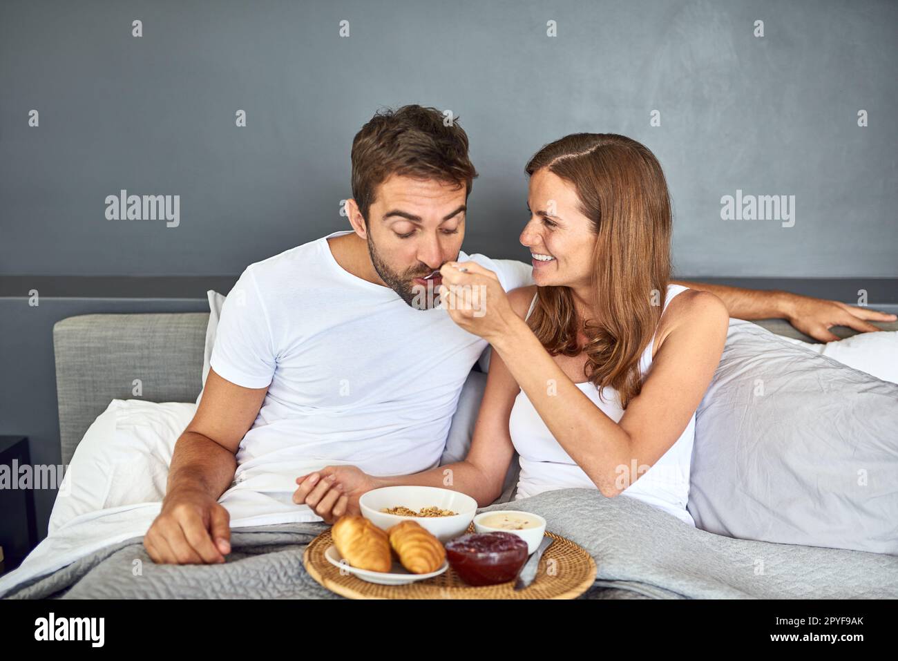 Nichts ist besser als ein gemütliches Frühstück im Bett. Ein glückliches junges Paar, das zu Hause zusammen im Bett frühstückt. Stockfoto