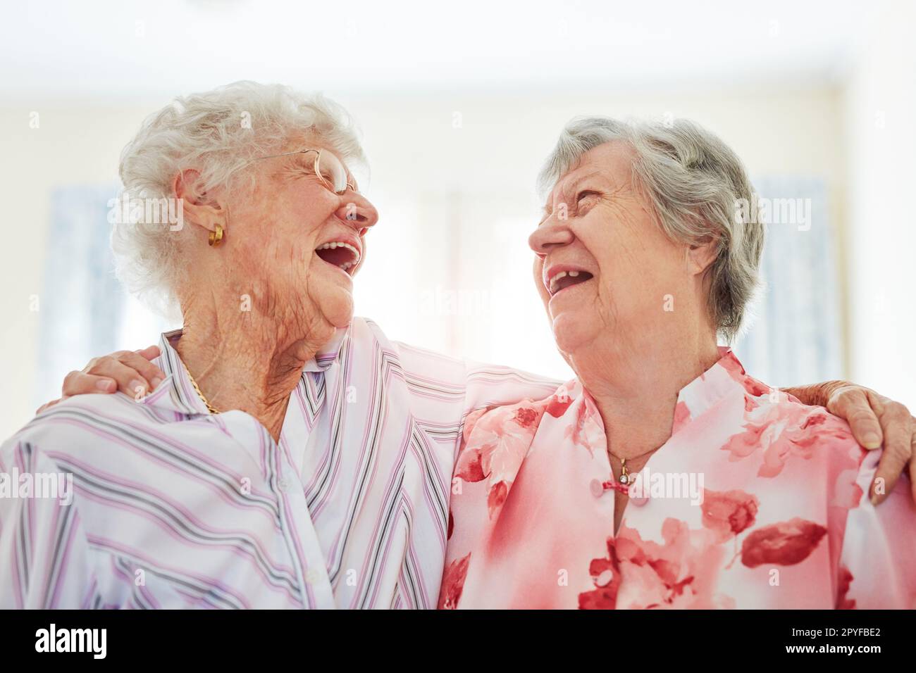 Was ist das Leben ohne Lachen? Zwei glückliche ältere Frauen, die sich zu Hause umarmen. Stockfoto