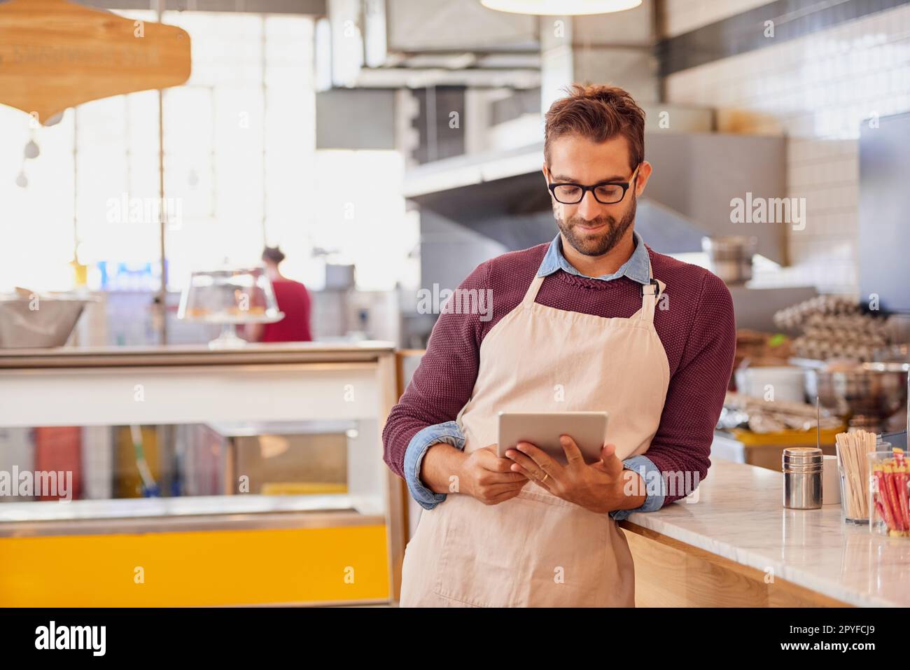 Erfolg steht heute auf der Speisekarte. Glücklicher junger Unternehmer, der ein Tablet in seinem Café benutzt. Stockfoto