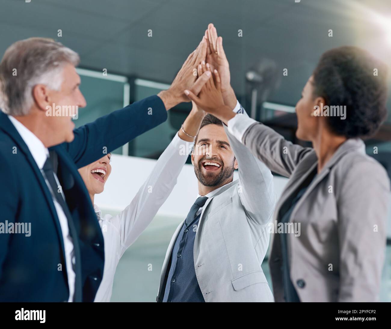 Harte Arbeit zahlt sich aus. Motivierte Arbeitskollegen lächeln und feiern mit einem High Five. Stockfoto