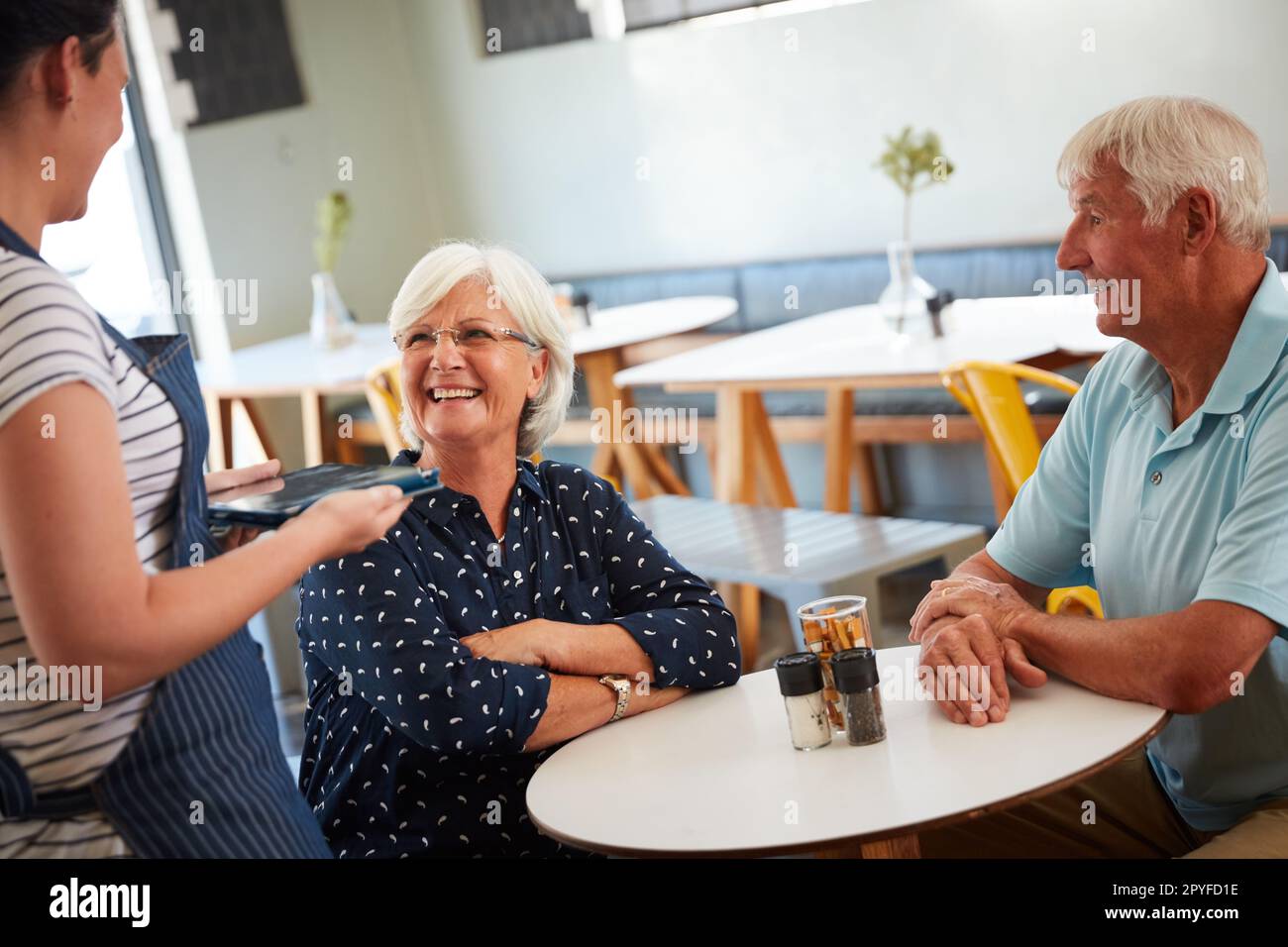 Dann wünsche ich den Rentnern etwas Besonderes. Ein älteres Paar, das von einer Kellnerin bedient wird. Stockfoto