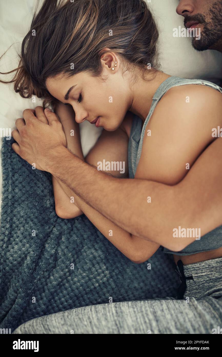 Bequem in den Armen ihrer Liebenden. Ein Foto eines liebevollen jungen Paares, das im Bett schläft. Stockfoto