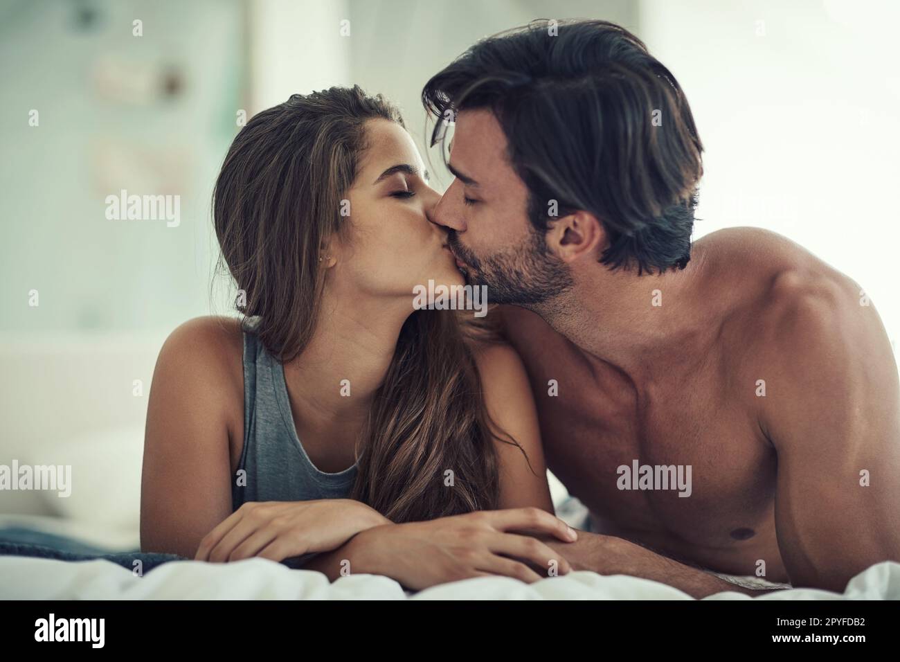 Küsschen. Ein liebevolles junges Paar, das intim in seinem Schlafzimmer ist. Stockfoto