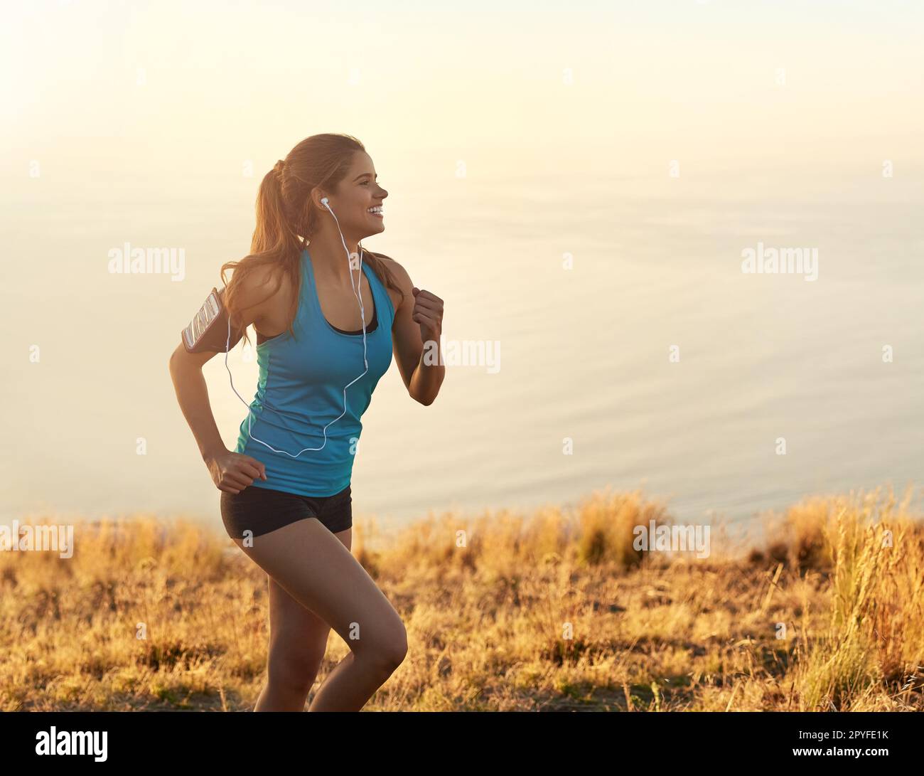 Steh auf, werde aktiv. Eine junge Frau, die beim Laufen Musik hört. Stockfoto
