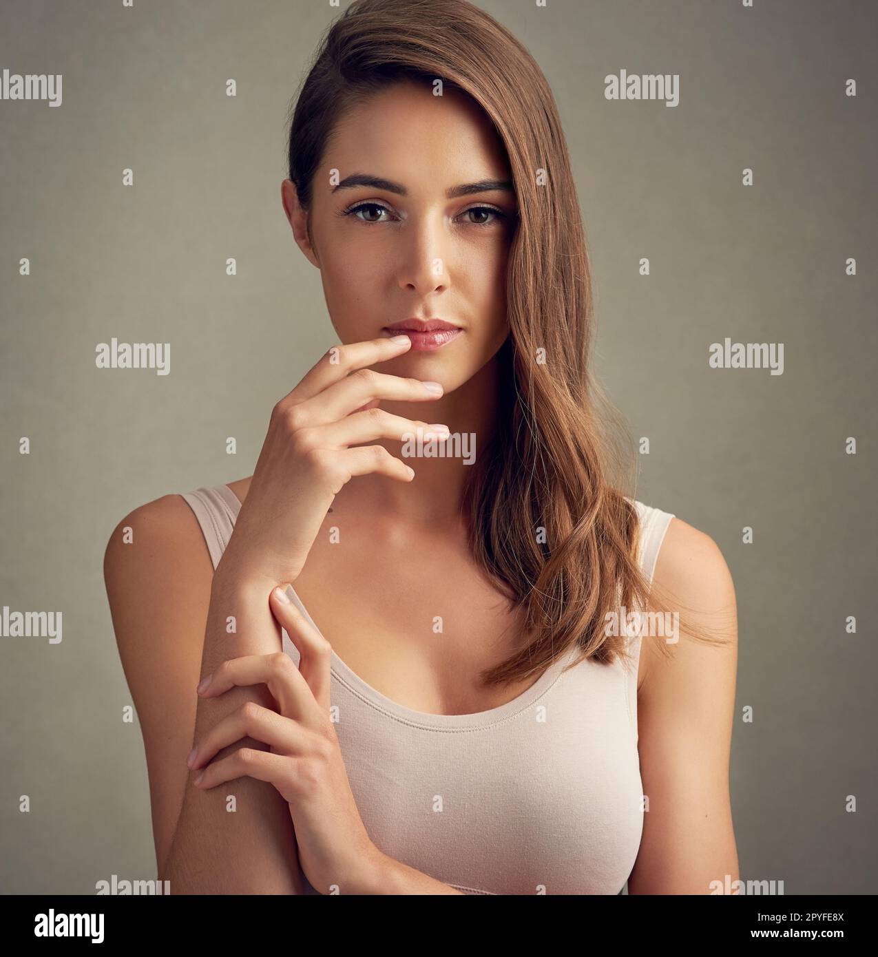 Sie erregt Aufmerksamkeit. Studioporträt einer attraktiven jungen Frau vor braunem Hintergrund. Stockfoto