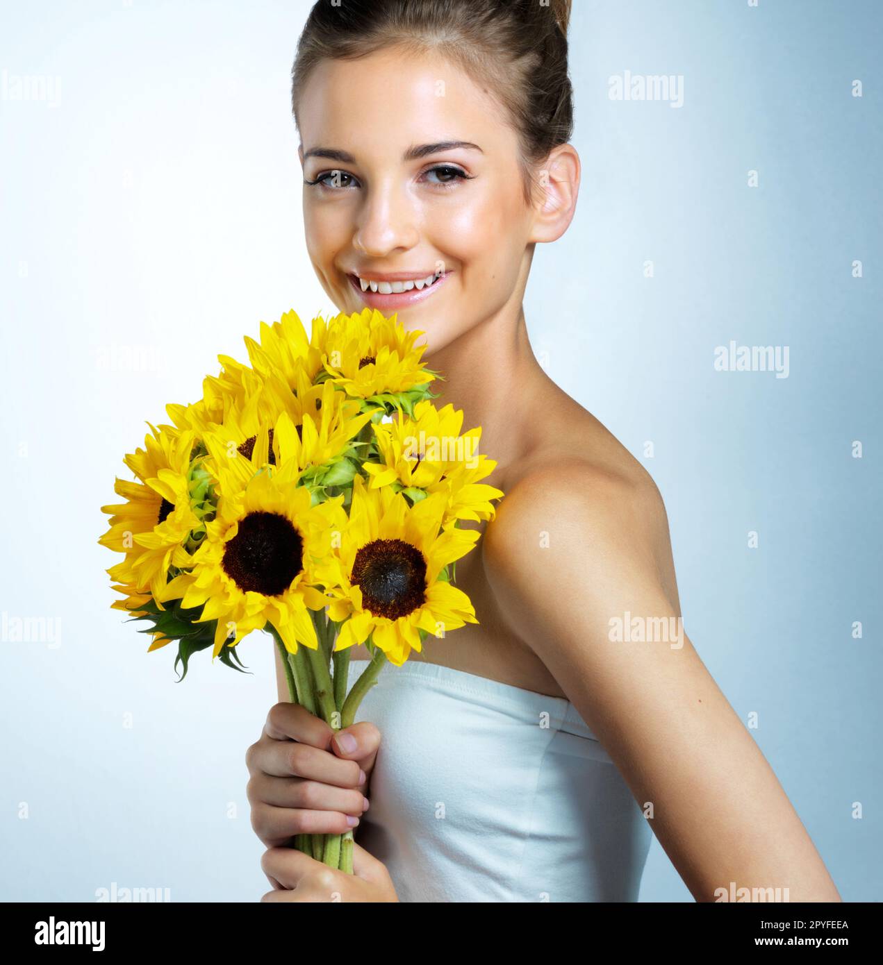 Blumen und Weiblichkeit. Studioporträt einer schönen jungen Frau mit einem Strauß Sonnenblumen. Stockfoto