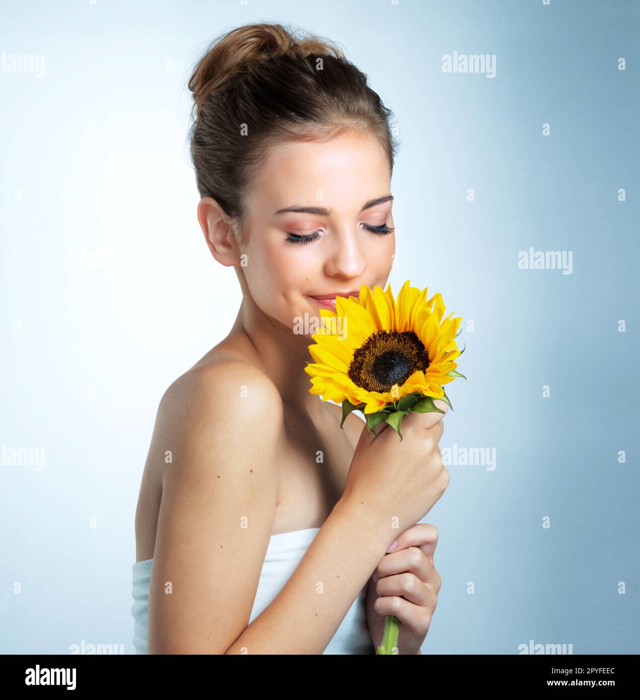 Schönheit, die von Natur aus perfekt ist. Studioaufnahme einer schönen jungen Frau, die eine Sonnenblume riecht. Stockfoto
