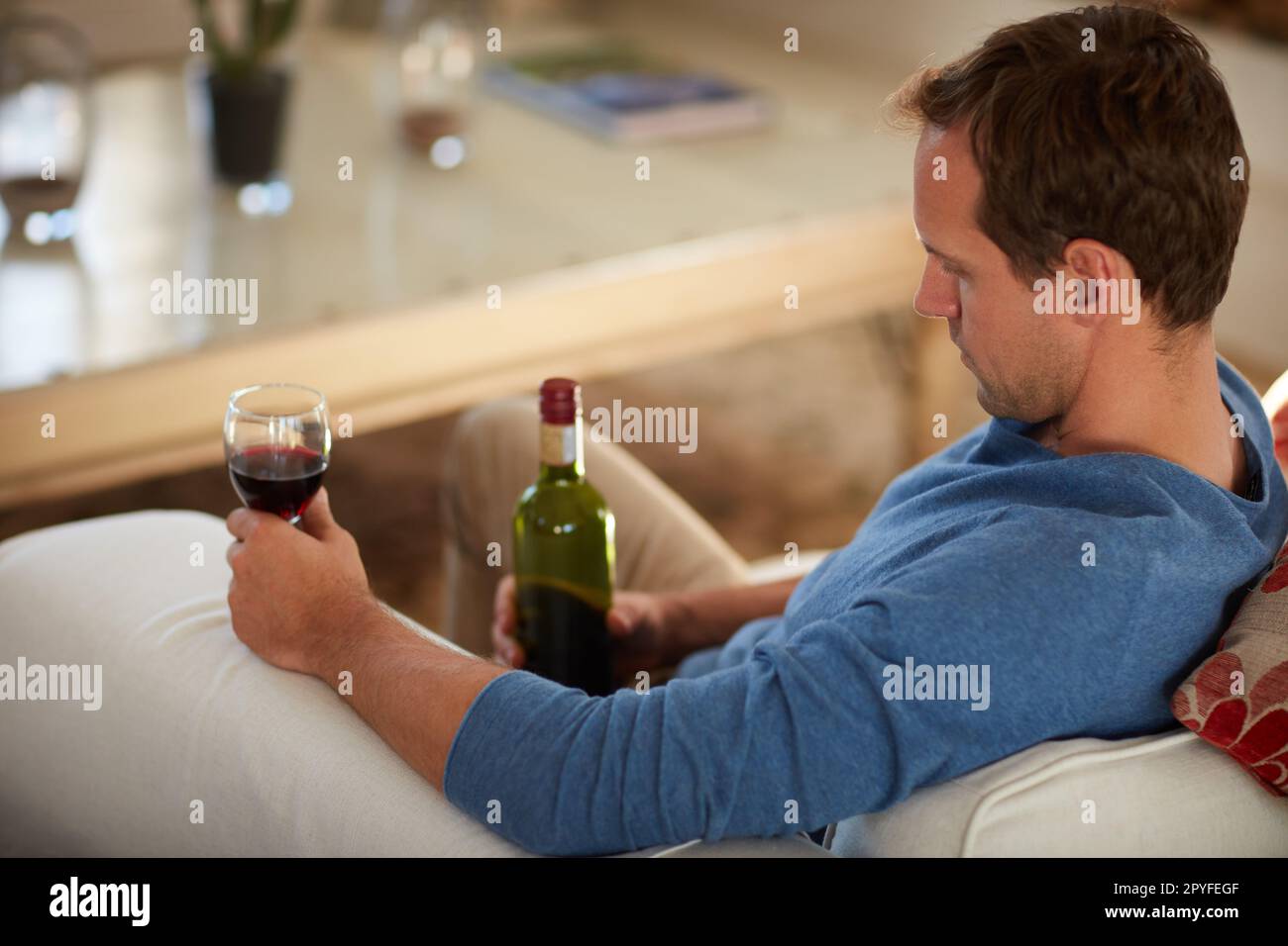 Er ertränkt seine Sorgen. Ein reifer Mann, der zu Hause Wein trinkt. Stockfoto