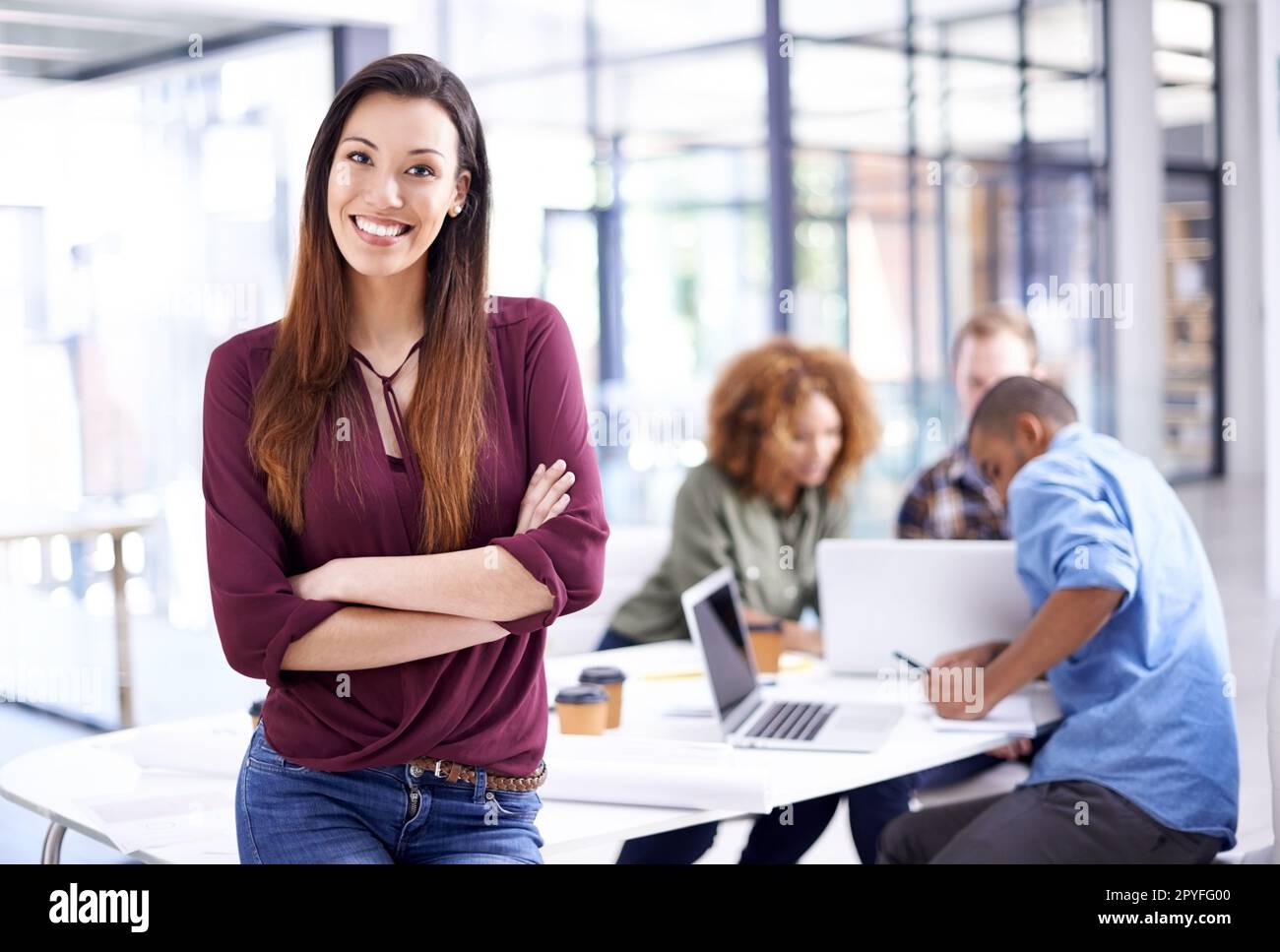 Nutzen Sie Gelegenheiten, um Ihr Unternehmen zum Erfolg zu führen. Porträt einer jungen Designerin, die im Büro mit ihren Kollegen im Hintergrund steht. Stockfoto