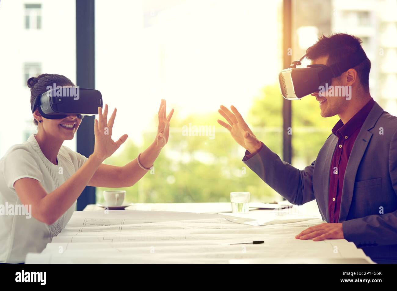 Die Reichweite der Technologie ist unbegrenzt. Zwei Geschäftsleute, die VR-Headsets tragen, während sie in einem Büro zusammenarbeiten. Stockfoto