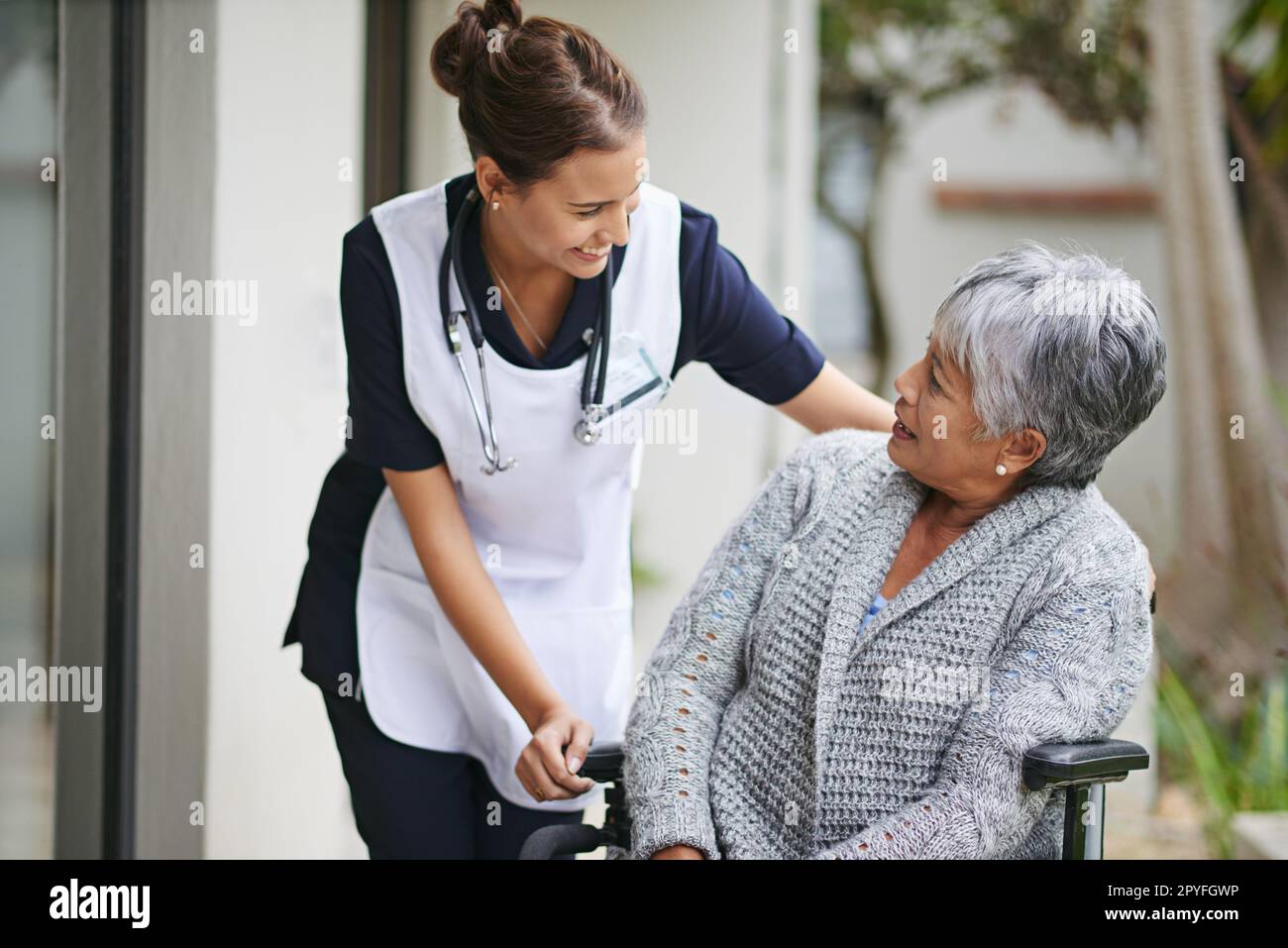 Nicht nur eine Pflegekraft, sie ist eine Begleiterin. Eine ältere Frau im Rollstuhl, die von einer Krankenschwester in einem Altersheim besucht wird. Stockfoto