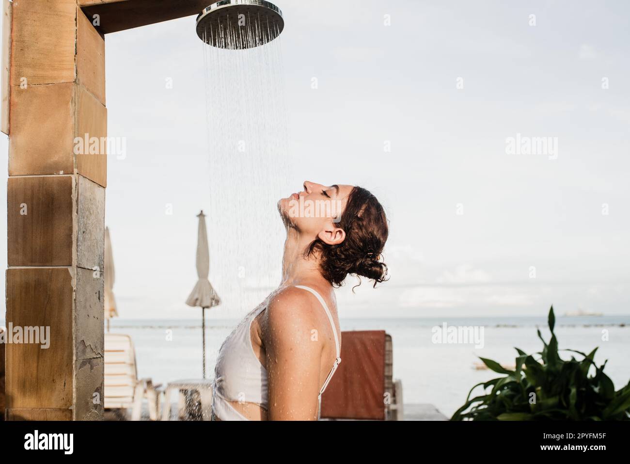 Eine Frau, die eine Außendusche in einem Traumurlaub-Resort nimmt. Stockfoto