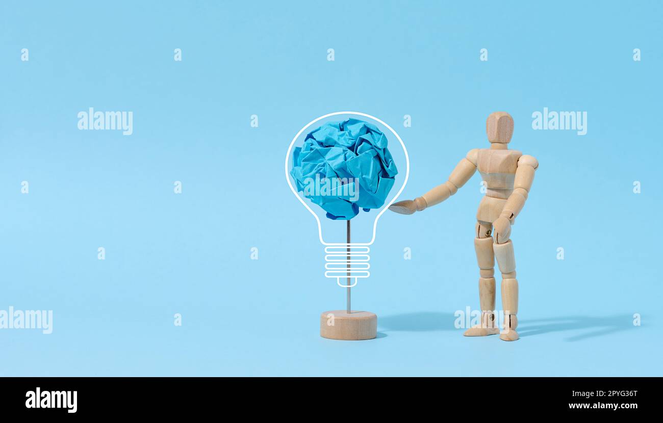 Eine Holzpuppe und eine zerknitterte Papierkugel, Suche nach neuen Lösungen und Ideen, Brainstorming Stockfoto