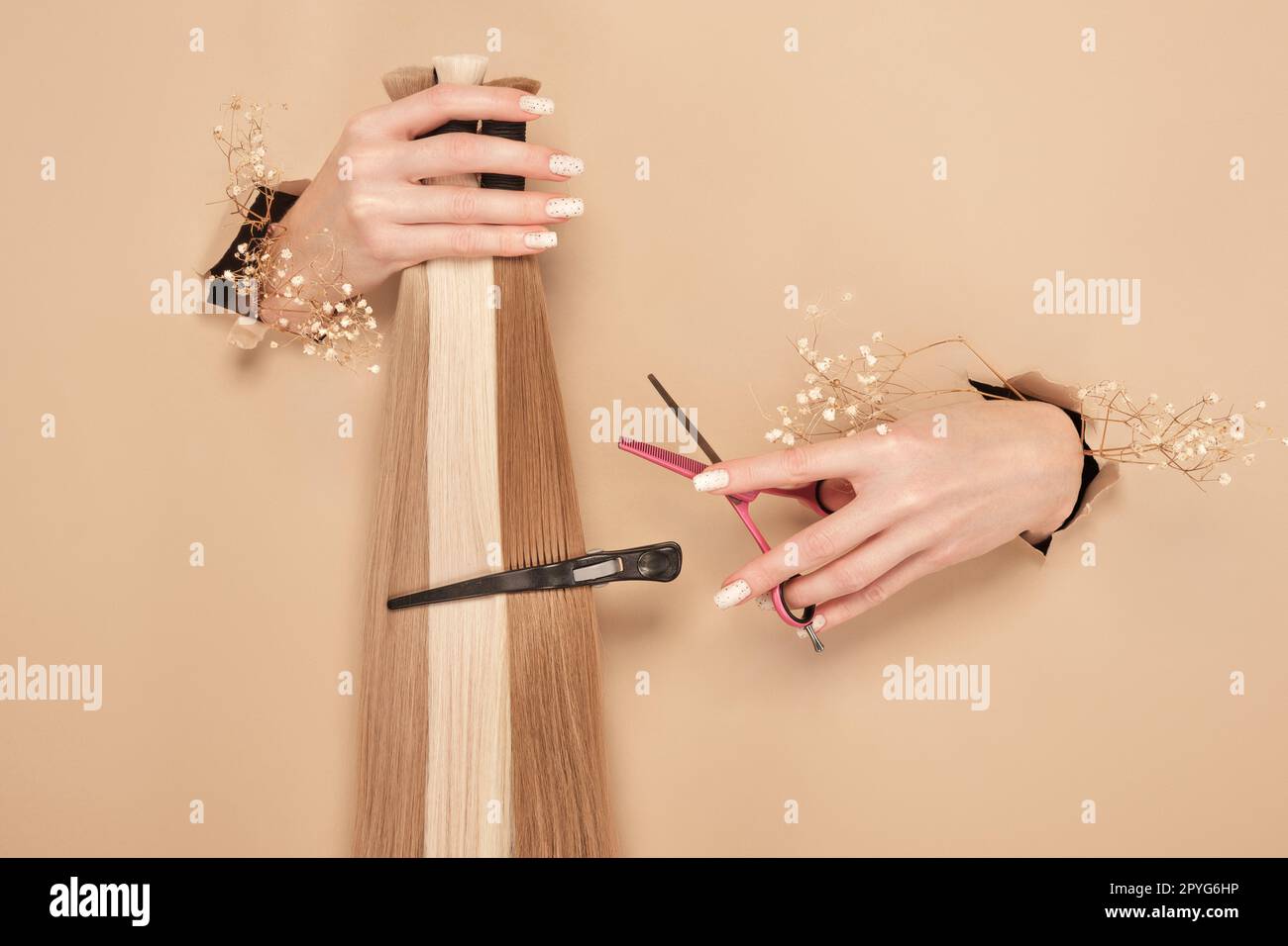 Hände mit Blumen halten Haarsträhnen für Verlängerungen auf beigefarbenem Hintergrund. Stockfoto