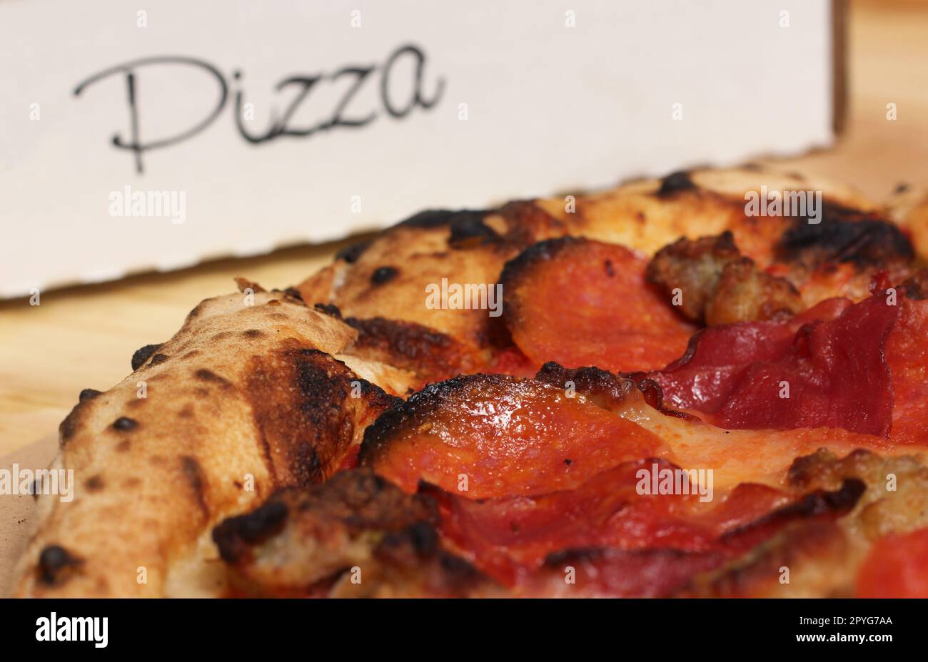 Frische Pizza auf einem Holztisch im Restaurant, geschnitten und fertig zum Essen Stockfoto