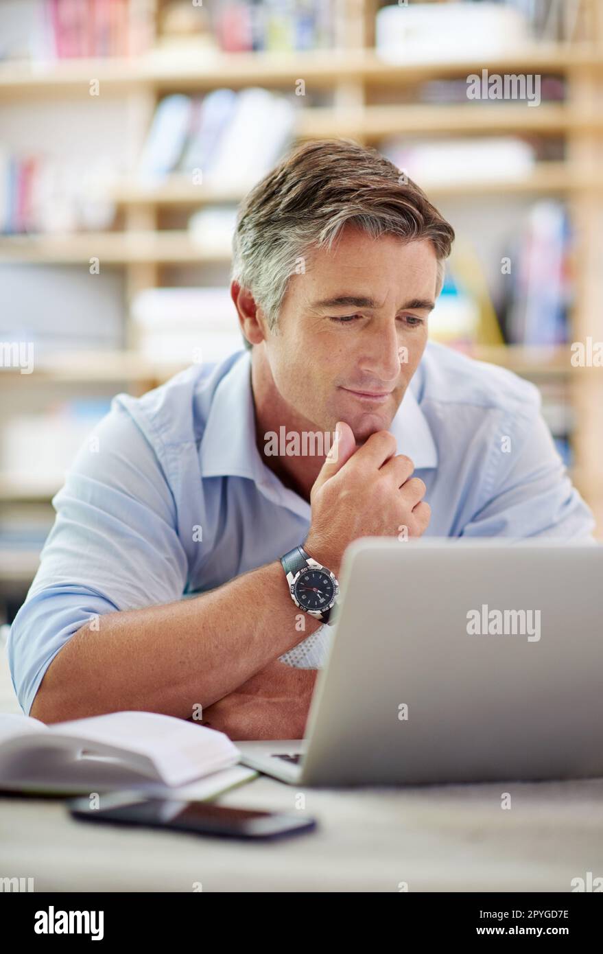 HES ist tief in das World Wide Web vertieft. Ein gut aussehender, reifer Mann, der mit einem Laptop auf dem Boden seines Wohnzimmers liegt. Stockfoto