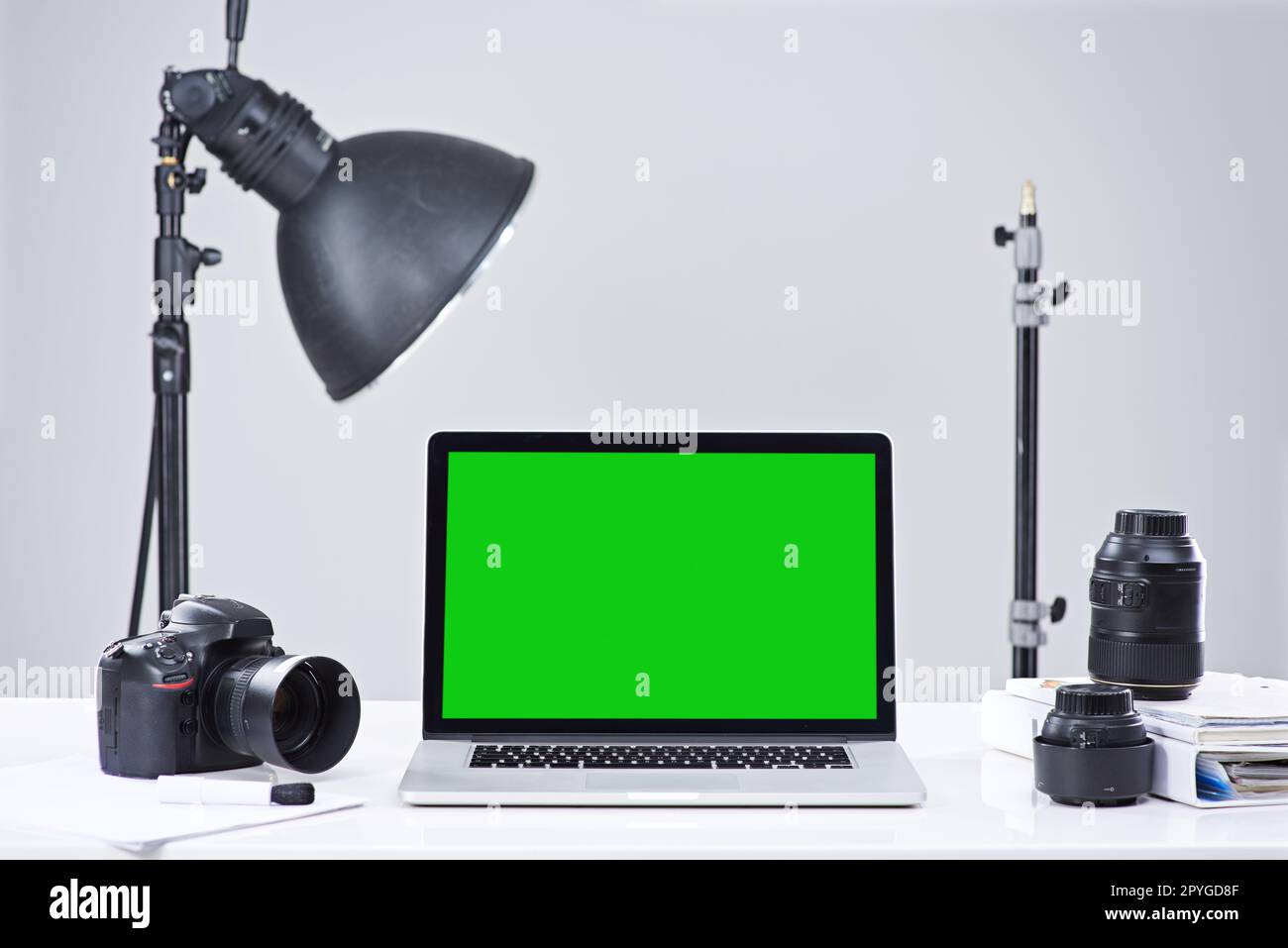 Verwandeln Sie Ihr Hobby in ein Geschäft. Ein Laptop mit grünem Bildschirm, umgeben von Fotoausrüstung. Stockfoto
