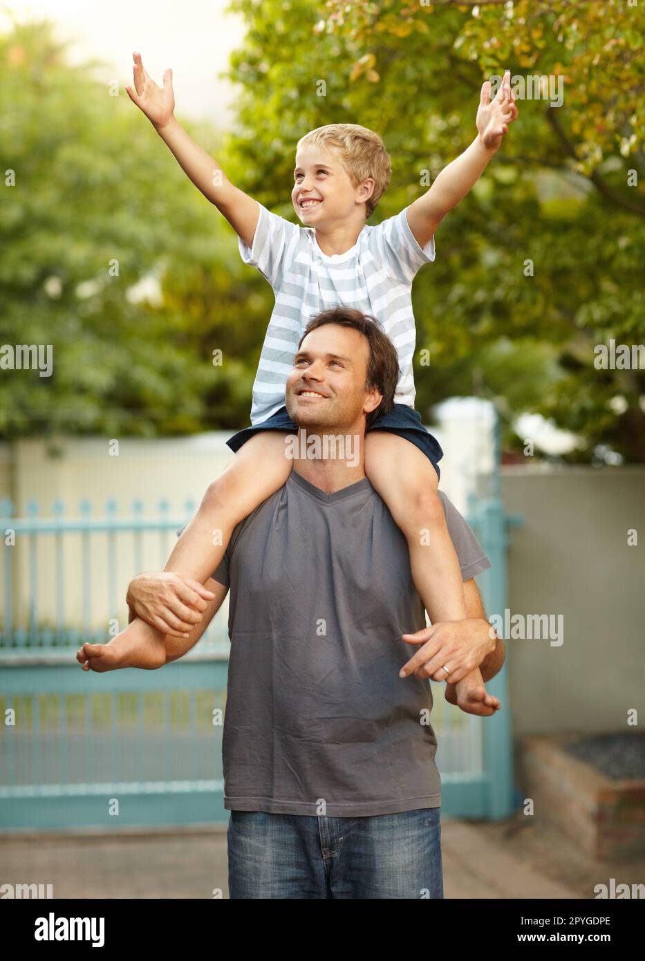 Dad gibt mir das Gefühl, ein König zu sein. Der Junge auf den Schultern  seines Vaters hebt die Hände in die Luft Stockfotografie - Alamy