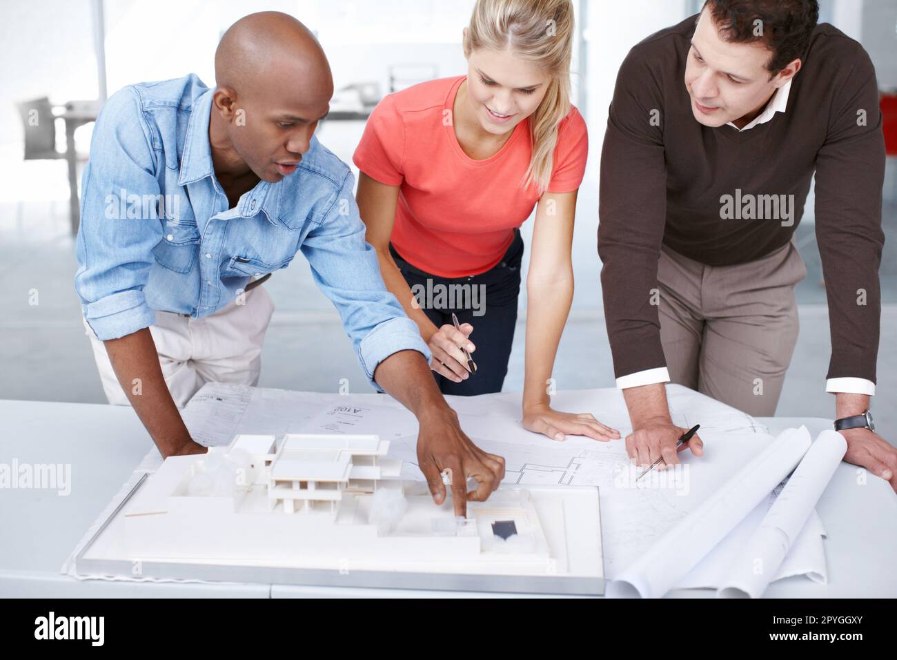 Ich schlage vor, wir ändern das Layout dort drüben... drei Architekten diskutieren ihr Architekturmodell. Stockfoto