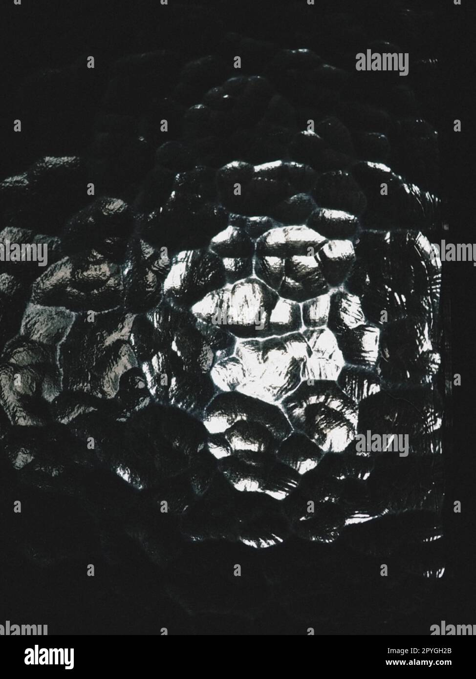 Wellglas, Rücklichtquelle. Das Spiel von Blendung und Reflexionen auf einer transparenten, unebenen Oberfläche. Dunkle und helle abstrakte asymmetrische, mehrfach beleuchtete Ebenen. Abstrakter seltsamer Hintergrund Stockfoto