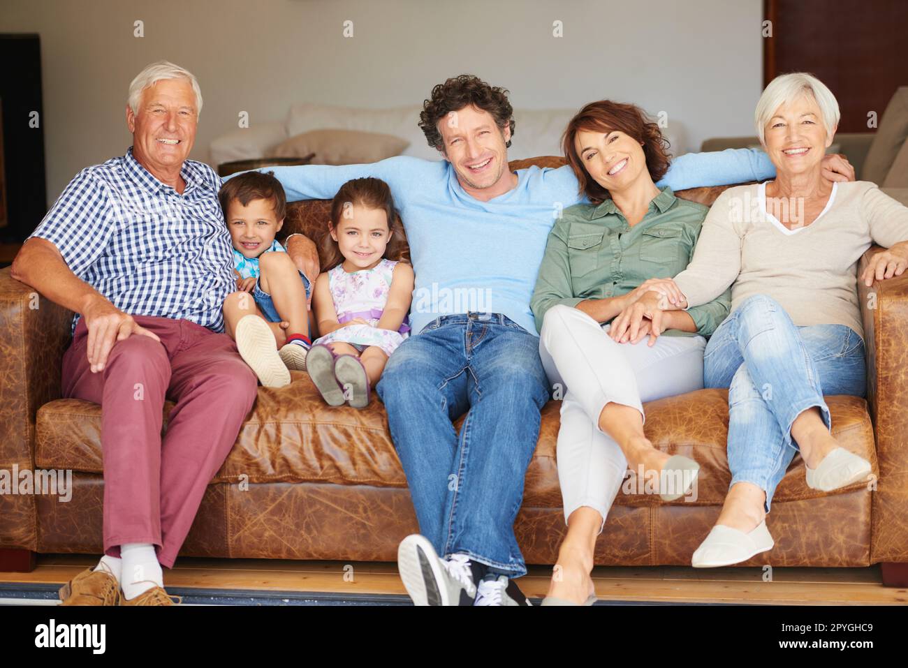 Zeit mit der Familie verbringen. Eine glückliche Familie mehrerer Generationen, die auf dem Sofa zusammensitzt. Stockfoto