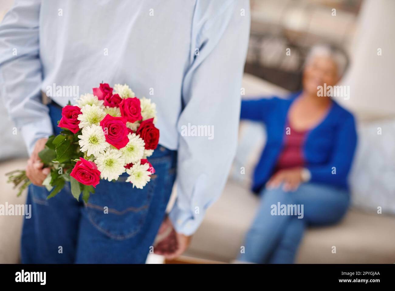 Die Liebe am Leben zu erhalten. Eine ältere Frau, die einen überraschenden Blumenstrauß von ihrem Mann bekommt. Stockfoto