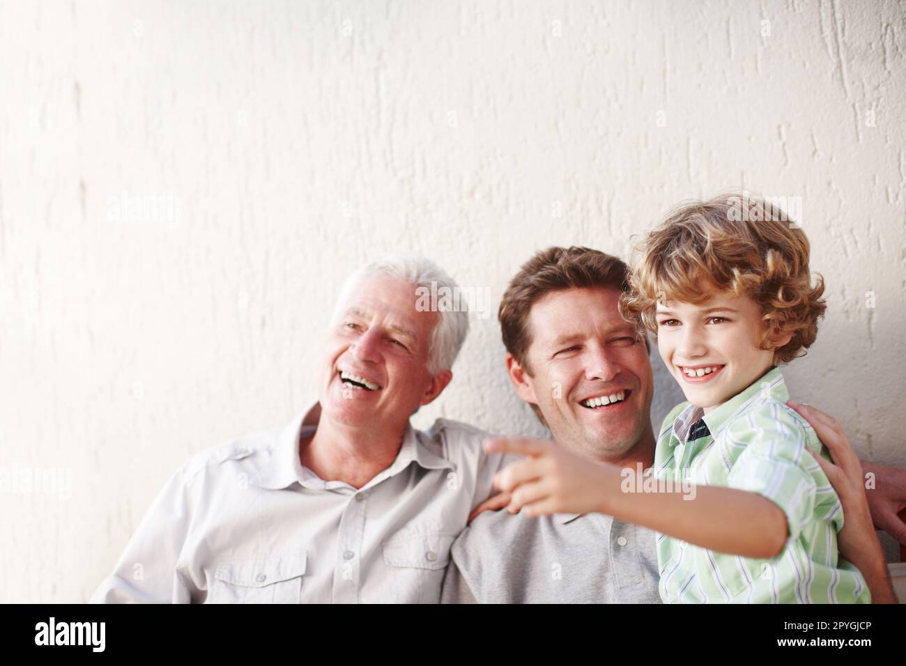 Sieh mal da drüben. Ein gutaussehender Mann, der bei seinem Vater und seinem Sohn sitzt. Stockfoto
