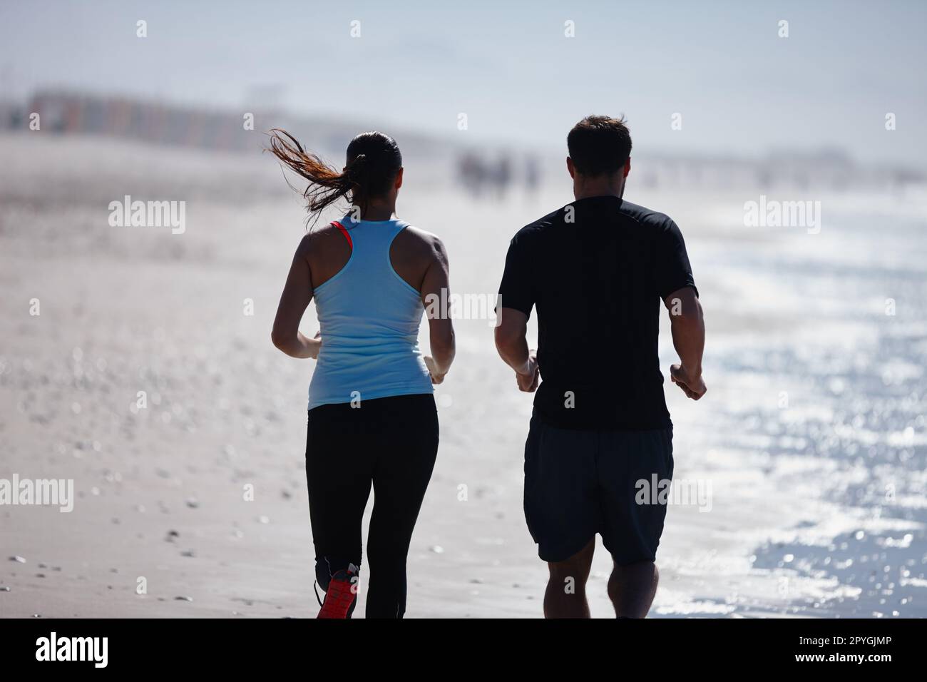 Zusammenhalten. Verkürzte Rückansicht eines Paares, das zusammen am Strand läuft. Stockfoto