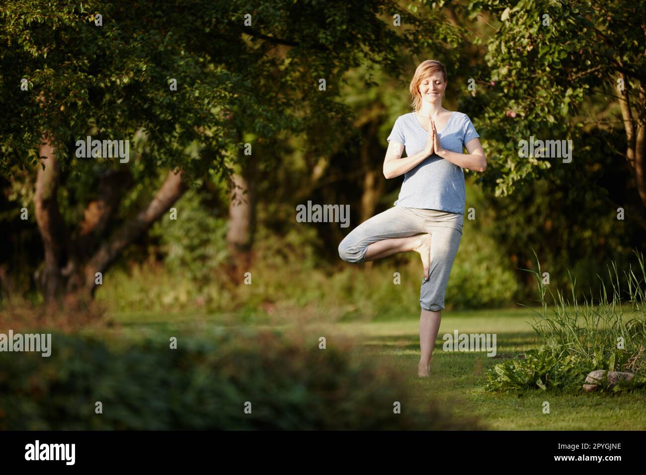 Sich in der Natur völlig entspannt zu fühlen. Eine attraktive Frau, die eine Yoga-Session in der Natur genießt. Stockfoto