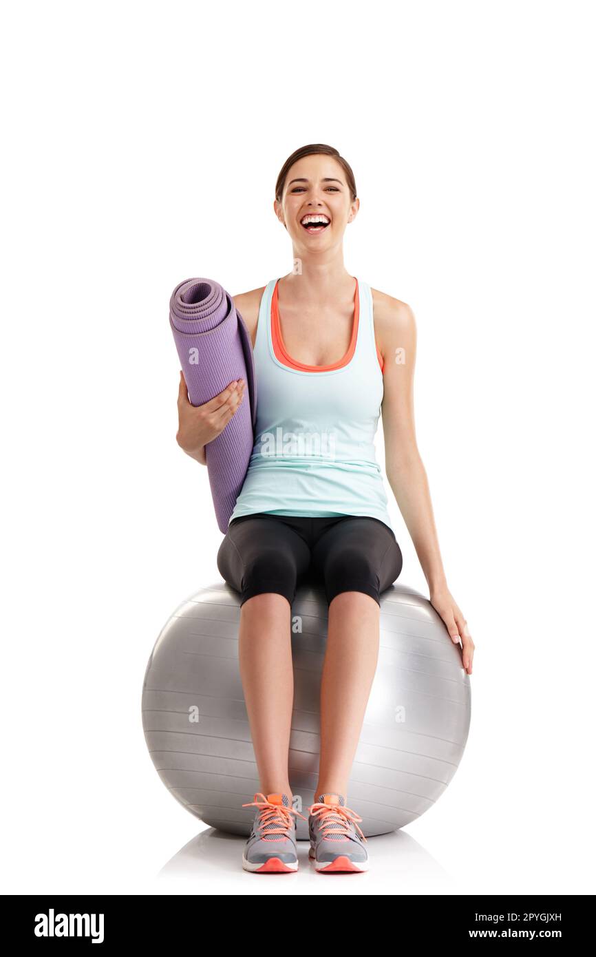 Dieses Gefühl nach einem guten Workout... eine junge Frau, die eine Yoga-Matte hält, während sie auf einem Trainingsball sitzt. Stockfoto