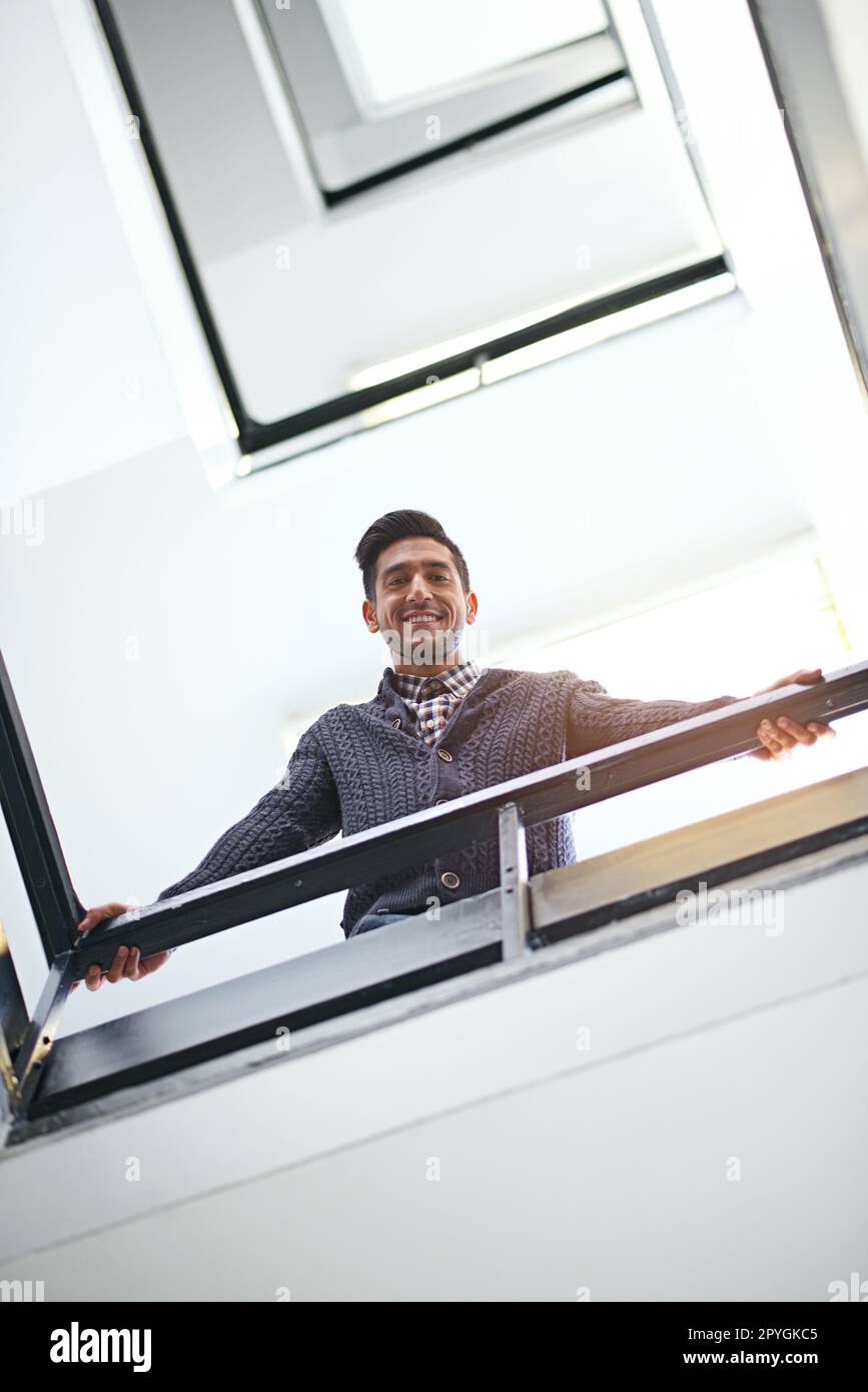 Wie läuft es da unten? Kleinwinkelporträt eines jungen Geschäftsmannes, der sich auf einem Treppenbannister lehnt. Stockfoto